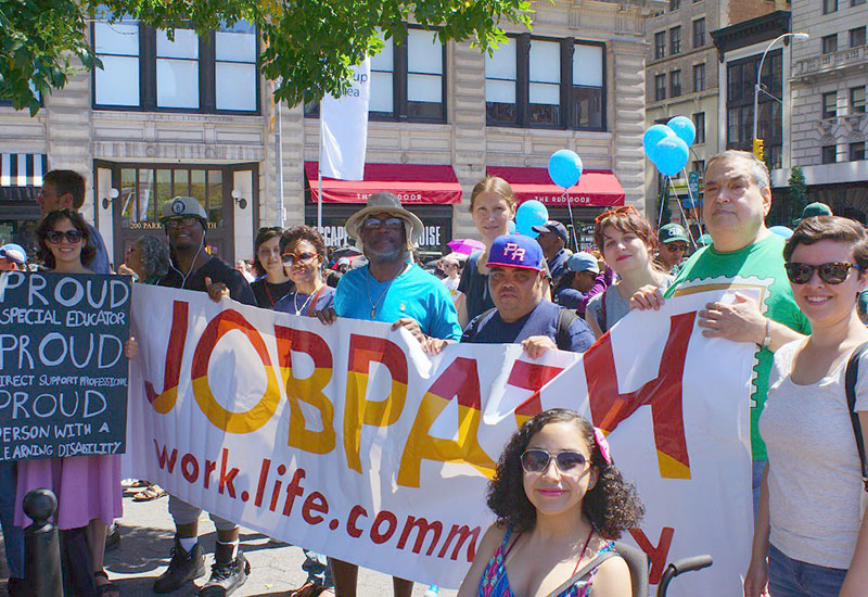 Photo of Job Path staff marching together at the Disability Pride Parade, holding a large Job Path banner