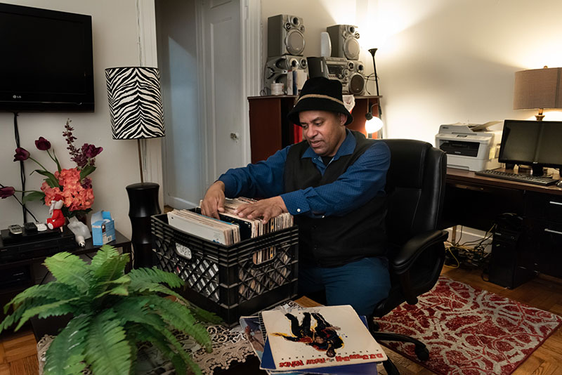 Robert at his cozy home, looking through his vinyl record collection.