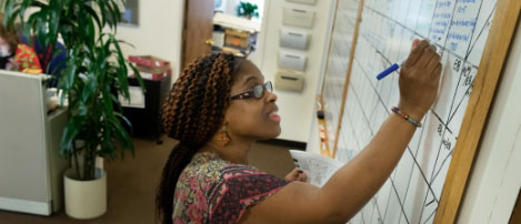 Nicola, a woman of color, working at the Shubert Organization by writing notes on a whiteboard